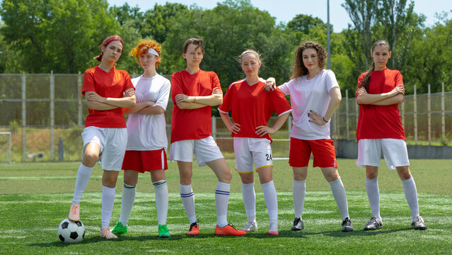 Women football team confidently posing on sunny outdoor field. Concept of women team identity, sports branding, group stance and unity, team-building visuals.