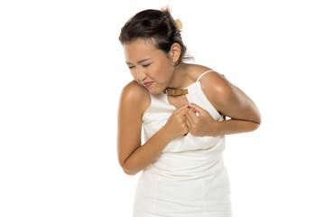 Asian woman holding chest in pain, studio shot on white background.