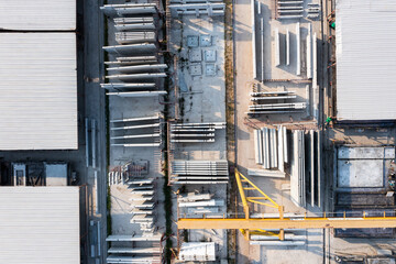 Top-down view of concrete precast yard with visible gantry cranes, warehouse rooftops, and assembly areas for structural components in construction industry.