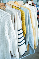 Warm cozy clothes on hangers. Knitted autumn sweaters. Home organization.