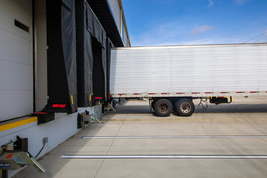 Back of white truck trailer on warehouse loading dock