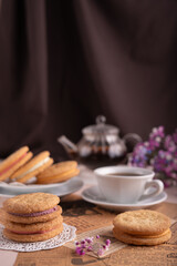 delicate afternoon tea setting with biscuits on newspaper and floral decor, featuring a teapot and cup in a warm, softly lit atmosphere, wrapped, crumbly, decorative, pleasure, peaceful, pastel