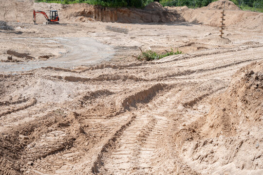 expansive construction site landscape with excavator amidst tracks and earth movement under clear skies, highlighting industrial development and earthwork processes, alteration, progress