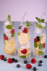 refreshing beverage trio with lemons, raspberries, blueberries, and mint in tall glasses on pastel background, celebration, party, decor, infused, cocktail, bright, contrast, set, beverages, lush