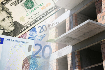 Rising construction costs. Euro and dollar banknotes over unfinished building structure. Expensive...