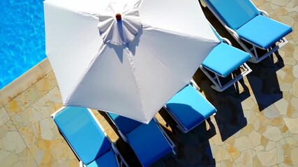 Poolside patio with white umbrella and teal lounge chairs - Powered by Adobe