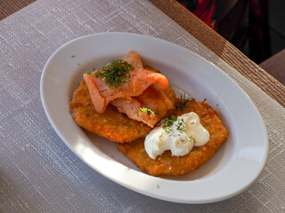Gourmet salmon dish with cream sauce and herbs elegantly plated on white ceramic in fine dining restaurant