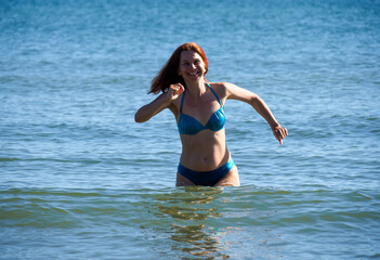 Athletic woman performing dynamic water exercise movements in pristine blue sea during summer day