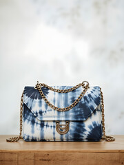 A blue and white tie dye bag with a gold chain