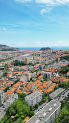 Obraz premium Aerial view of a vibrant coastal city with colorful rooftops, lush greenery, and distant hills, showcasing urban architecture and natural beauty in harmony