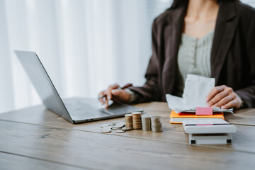 Unrecognizable woman holds receipts pencil uses laptop plans budget manages expenses calculates...