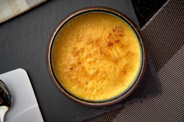 Deliciously Caramelized Dessert with Smooth, Creamy Texture Served in a Dark Ceramic Bowl on a Stylish Black Surface