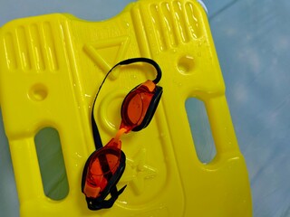 Bright Yellow Kickboard with Orange Tinted Goggles, Water Droplets, Swimming Equipment