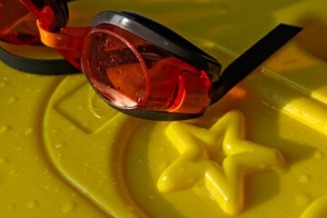 Orange Tinted Swimming Goggles Resting Beside a Yellow Starfish on a Yellow Surface
