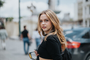 A confident young woman with flowing hair stands outdoors in an urban environment, exuding style...