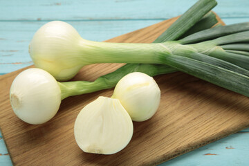 Green onion on cutting board on blue wooden background.