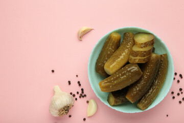 Marinated pickled cucumber with garlic on pink background.