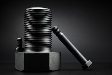 Variety of large black steel screws on black background.