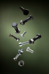 Variety of large steel screws and bolts flying on green background.