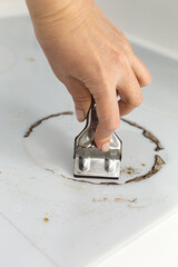 Woman cleaning electronic ceramic stove surface using special steel scraper