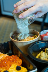 Pouring Sauce Over Asian Cuisine in Takeout Containers