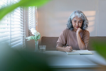 Senior Woman Reviewing Documents and Taking Notes at Home