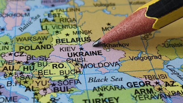 Closeup of pencil tip touching ukraine county location or territory mark drawing on a map with some ukrainian city name word or text written on the surface. Travel tourism creative concept.