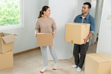 Moving house, relocation. Couples hold carton box contain equipment for new condominium, inside the...