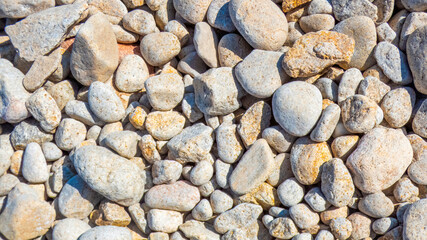 A close-up view of smooth sea-worn pebbles scattered across a sunlit Mediterranean beach