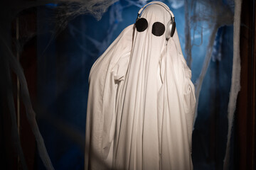 Funny halloween ghost in dark room with smoke and cobweb dancing and listening music in headphones....