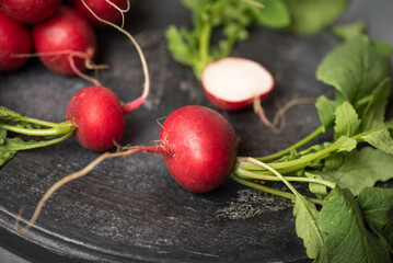Fresh Radishes Cut In Half Displayed On A Dark Plate With Greenery