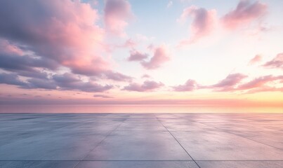 Empty paved area at sunset. Soft, pastel-colored clouds fill the sky above a flat expanse of light gray paving stones