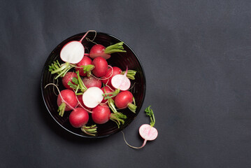 Bowl Of Fresh Radishes With Sliced Halves On Black Background