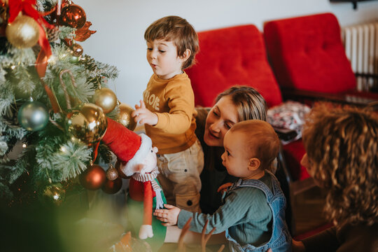 A family shares delightful moments decorating their Christmas tree, radiating a festive and heartwarming holiday ambiance for the season.