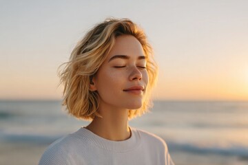 Obraz premium woman stands on serene beach at sunrise eyes closed embracing morning light representing tranquility of intuitive awakening