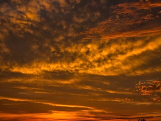 Obraz premium Fiery sunset sky with dramatic clouds and silhouetted horizon