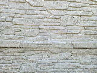 Textured stone wall background featuring white stone bricks arranged in a pattern. Ideal for design projects, interior decor, or architectural presentations.
