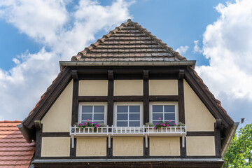 Half-timbered house with flower boxes. A charming half-timbered house with gable windows and colorful flower balconies under a blue sky. The traditional architecture exudes coziness.
