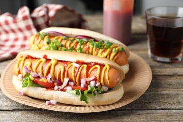 Delicious hot dogs with sauces, lettuce and onion on wooden table, closeup