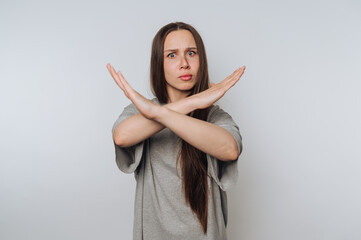 Woman with long hair making an X gesture with arms, wearing a gray shirt.