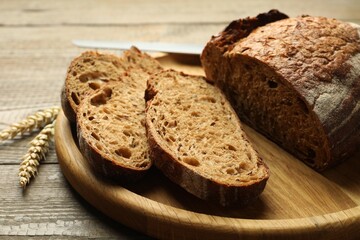 Pieces of fresh bread, spikes and knife on wooden table, closeup