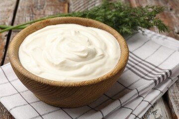 Tasty sour cream with dill on wooden table, closeup