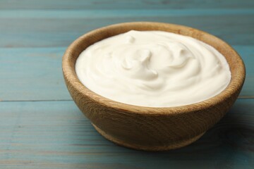 Tasty sour cream on blue wooden table, closeup