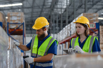 Male and female staff wearing safety gear conducting inventory check in vehicle parts warehouse...