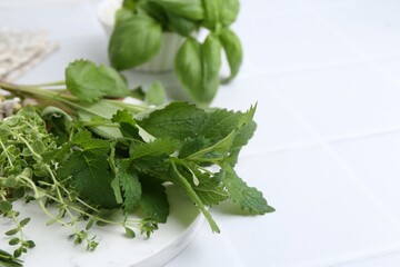 Different fresh green herbs on white tiled table, closeup. Space for text