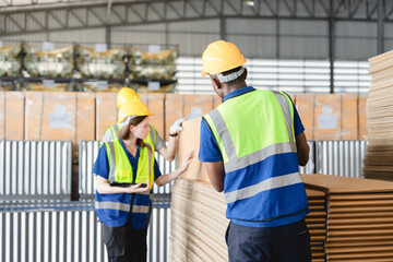 Warehouse workers preparing cardboard packaging for shipping, wearing safety gear inside logistics facility, Industrial logistics teamwork.