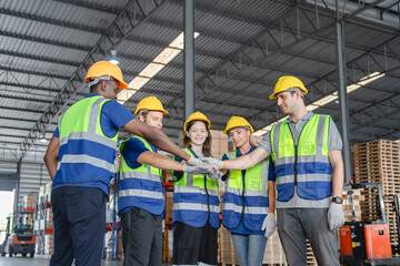 Close-up image of diverse construction workers joining hands in teamwork gesture, showcasing unity and collaboration at an industrial site under bright lighting.