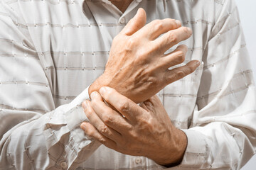 Arthritis symptoms, suffering from pain. The hands of the senior man massage wrist. Inflamed male...