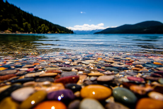 Close-up view of colorful pebbles in clear river water - Powered by Adobe