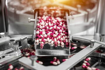Close up of pink and white capsules pills in the pills packaging machine, pharmacy medicine capsule pill in production line at medical factory.